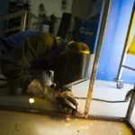 Un chaudronnier-soudeur au travail sur une pièce métallique, dans un atelier